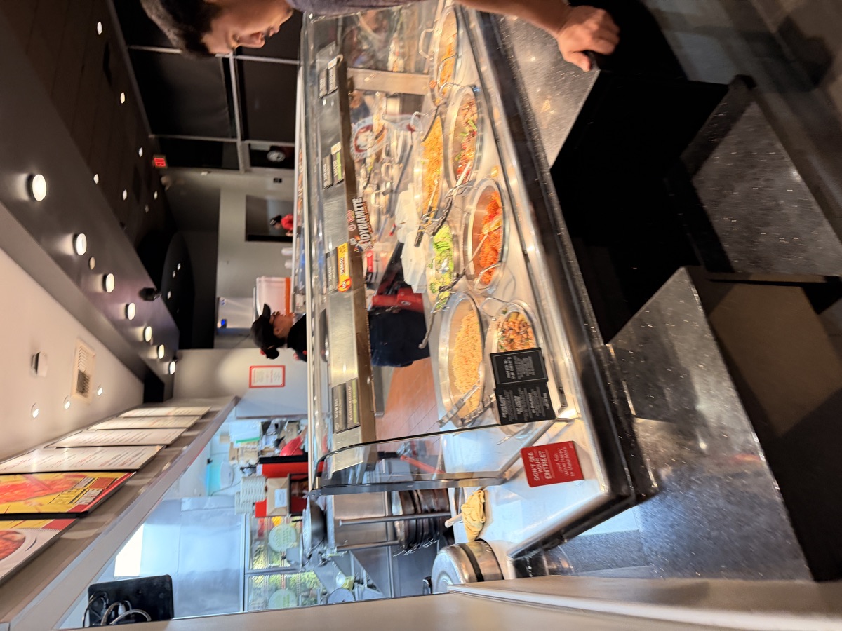 The Panda Express serving counter showing trays of different dishes lined up behind the glass